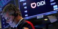 Ein Börsenhändler mit Headset in der New Yorker Börse - uaf einer Anzeigetafel ist das Logo des Tech-Unternehmend Didi zu sehen