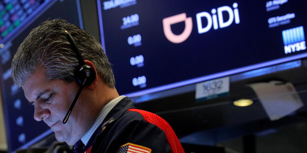Ein Börsenhändler mit Headset in der New Yorker Börse - uaf einer Anzeigetafel ist das Logo des Tech-Unternehmend Didi zu sehen