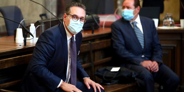 Mann im Anzug und mit Maske im Gerichtssaal.