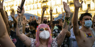 Demonstrierende mit Mund-Nasenschutz heben ihre Arme