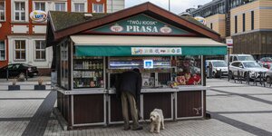 Ein Mann mit Pudel vor einem grünen Kiosk