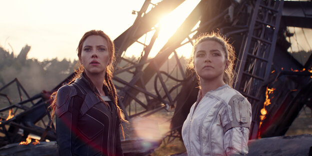 Filmausschnitt mit den beiden Schauspielerinnen Scarlett Johansson und Florence Pugh vor einem brennenden Metallgerüst