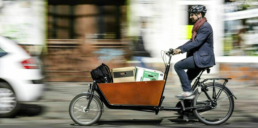 Ein Mann faehrt mit einem beladenen Lastenrad