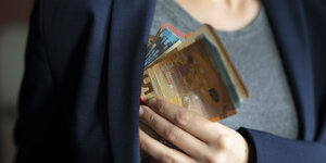 Ein Mann steckt sich ein Bündel Euro-Scheine in die Innentasche seines Jackets