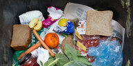 Brotscheiben, eine Orange, eine Windel, Möhren, eine Plastiktüte und mehr bilden einen Müllhaufen