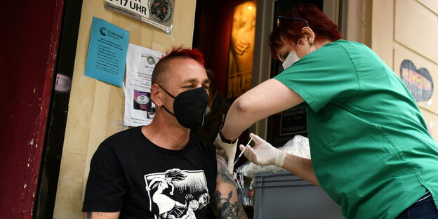 Eine Krankenschwester spritzt jungen Mann mit Tätowierung