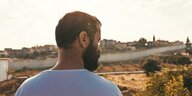 Szene aus "200 Meters": Mann blickt vom Balkon auf eine Grenzmauer in Israel