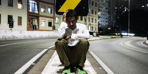 Luciano Valério sitzt auf einer Straße bei Dunkelheit