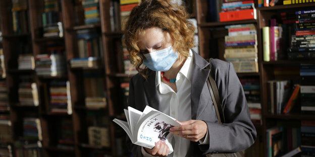 Emi (Katia Pascariu) liest im Buchladen mit OP-Maske in einem Buch über Sex.