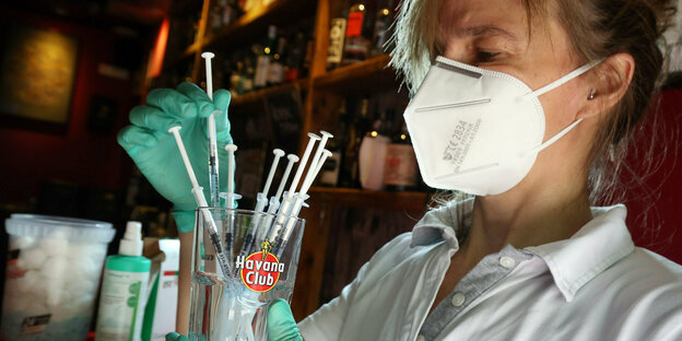 Eine medizinische Fachangestellte sortiert in der Revolte-Bar im Berliner Bezirk Friedrichshain Spritzen mit dem Impfstoff Johnson & Johnson in einem Havanna-Club Glas
