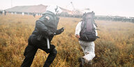 Ein Polizist verfolgt einen Demonstranten der übers Feld flüchtet