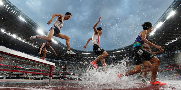Athleten springen über Hürden in einem Stadion in Tokio ohne Zuschauer