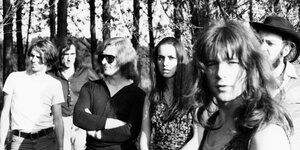 MusikerInnen der Rockgruppe Amon Düül stehen vor Böumen