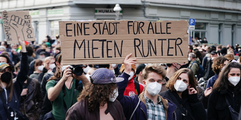 Ein Mann hält auf einer Demonstration ein Schild hoch mit der Aufschrift "Mieten runter"