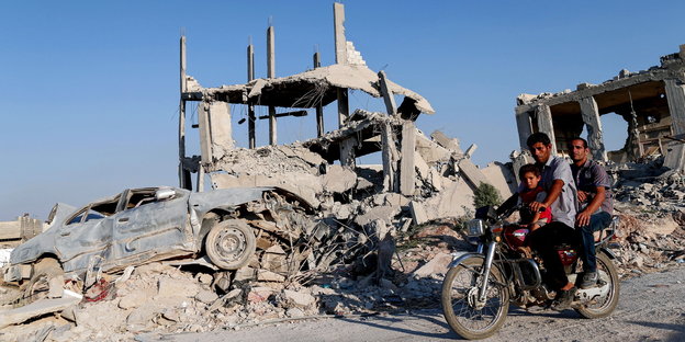 Männer aus Kobane vor einer Hausruine