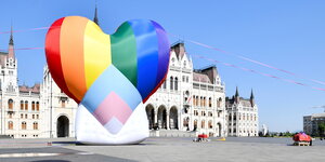 ein großes Luftballon Herz in Regenbogenfarben schwebt über dem Parlament