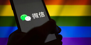 Smartphone mit WeChat Logo vor Regenbogenflagge