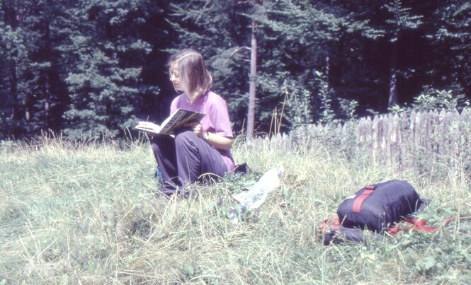 Eine Frau sitzt auf einer Wiese und liest ein Buch