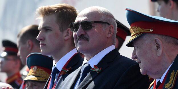 Lukaschenko steht mit Sonnenbrille am Rand einer Parade