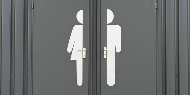 Auf zwei Türen sind zwei in der Mitte abgetrennte Symbole für Frau und Mann aufgeklebt