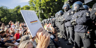 Hand streckt Polizisten ein Grundgesetz entgegen