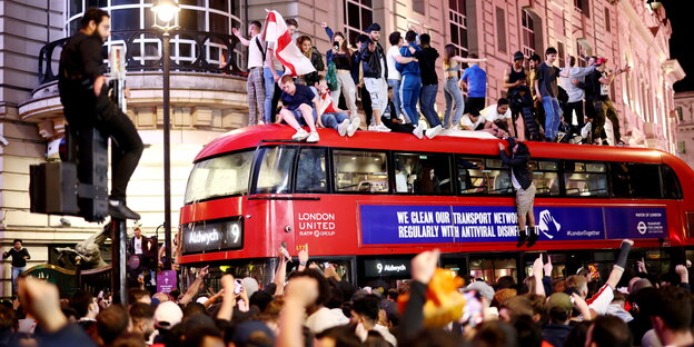 Dänische Fussballfans toben auf einem roten Londoner Bus, der durch eine Menge fährt