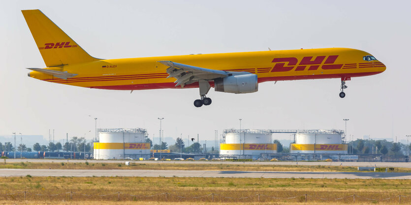 Ein riesiges Flugzeug mit der Aufschrift "DHL" hebt vom Boden einer Startbahn ab.