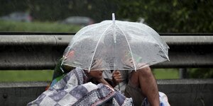 Drei Menschen unter einem Regenschirm