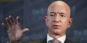 Jeff Bezos, Chef von Amazon, hebt eine Hand