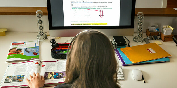 Ein Mädchen sitzt zu Hause vor einem Rechner