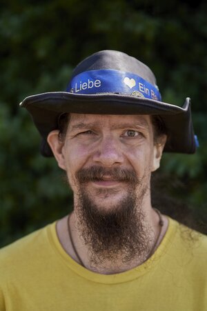 Steinmüller trägt einen schwarzen Hut mit blauem Band "Ein Band aus Liebe" steht darauf Steinmüller trägt einen schwarzen Hut mit blauem Band "Ein Band aus Liebe" steht darauf