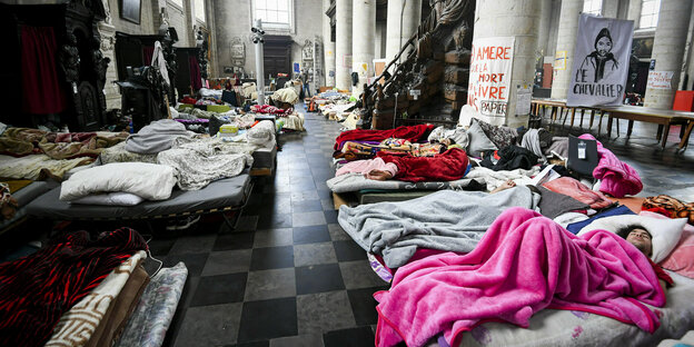 Menschen haben ein Schlaflager auf Matratzen in einer Kirche aufgeschlagen