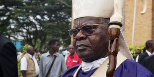 Laurent Monsengwo nach einem Gottesdienst mit violetter Robe, weißer Mütze und Stab