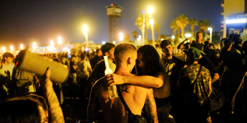 Touristen und Einheimische feiern Nachts am Strand von Barcelona