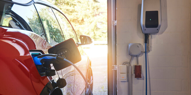 Ein Elektroauto beim Laden an der Wallbox zuhause in der Garage