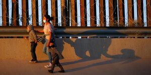 Eine Mutter rennt mit ihren Kindern vor dem Grenzzaun bei El Paso