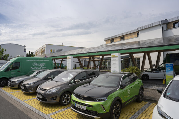 Solarpaneele auf einem Dach, darunter Autos an Ladstationen