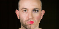 Portrait einen Mannes, der eine Gesichtshälfte weiblich geschminkt hat