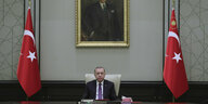 Der türkische Präsident Recep Tayyip Erdogan sitzt an einem großen Tisch, rechts und links von ihm steht jeweils die türkischen Flagge