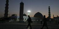 Silhouetten zweier Männer vor einer Moschee in der Abenddämmerung