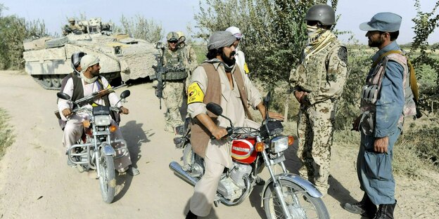 Ein Dolmetscher der Bundeswehr (2.vr), Bundeswehrsoldaten und afghanische Polizei nahe Kundus, 2011 unterhalten sich mit zwei Männern auf Motorrädern