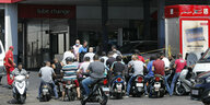 Fahrer von Motorrollern stehen Schlange an einer Tankstelle