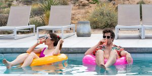 Szene aus dem Film "Palm Springs" - die Schauspieler Cristin Milioti und Andy Samberg liegen in bunten Reifen im Swimmingpool