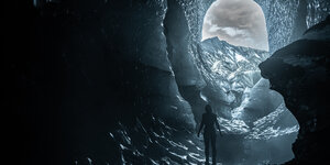 Eine nackte Frau steht in einer Gletscherhöhle.
