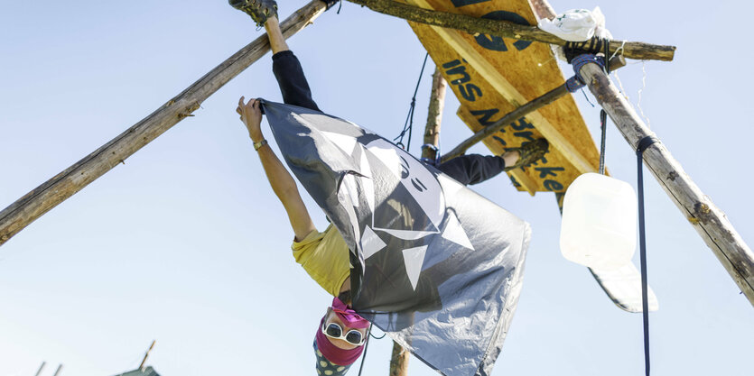 Vermummter klettert über Kopf auf Gestell