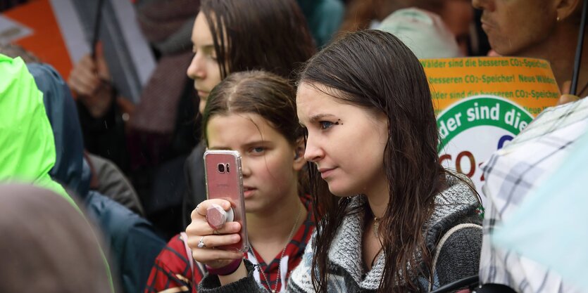 Jugendliche auf einer Demo von Fridays for Future machen ein Foto von anderen Demonstrierenden