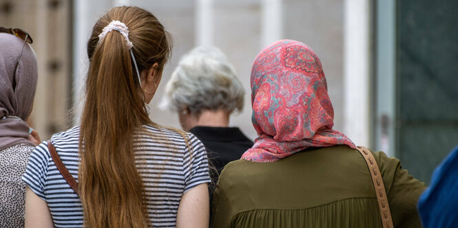 Frauen unter anderem eine mit Kopftuch gehen eine Strasse entlang