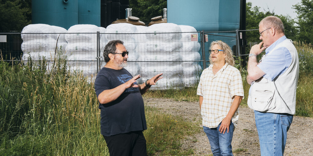 3 Männer diskutieren vor einer technischen Anlage