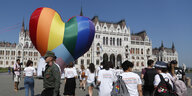 Aktivistinnen und Aktivisten gehen an einem großen regenbogenfarbenen Herz vorbei, das vor dem Parlamentsgebäude in Budapest aufgestellt wurde