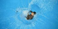 Ein Kind springt in einen Pool und das Wasser spritzt hoch